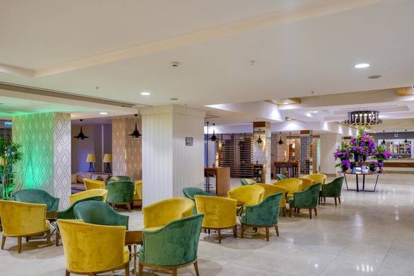 Lobby des Grand Park Lara Hotels mit farbenfrohen Sesseln und Pflanzen.