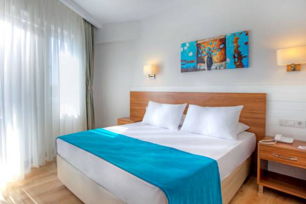 Schlafzimmer im Grand Park Lara Hotel mit blauer Bettdecke und weißen Kissen auf einem Bett mit Kopfteil.