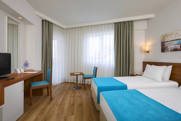 Innenansicht eines Doppelzimmers im Grand Park Lara Hotel mit zwei Betten, Schreibtisch und Fernseher.