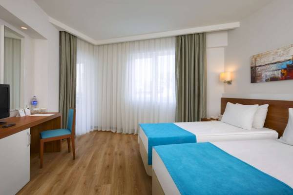 Innenansicht eines Zimmers im Grand Park Lara Hotel mit zwei Betten und einem Schreibtisch.