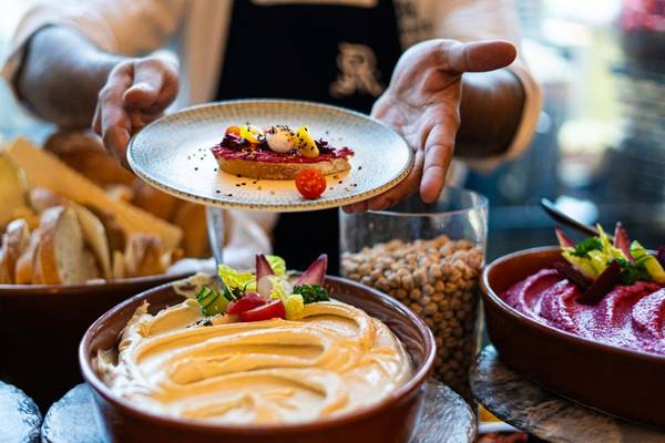 Ein Kellner präsentiert ein Gericht auf dem Buffettisch des St. Regis Doha.