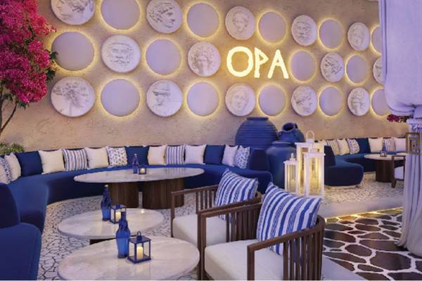 OPA Lounge im St. Regis Doha mit blauen Sofas, weißen Kissen und dekorativen Wandtellern.