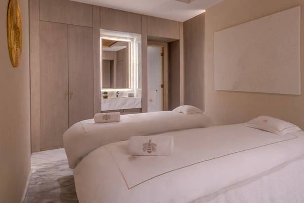 Massageraum im St. Regis Doha mit zwei Massageliegen, weißen Handtüchern und einem großen weißen Wandbild.