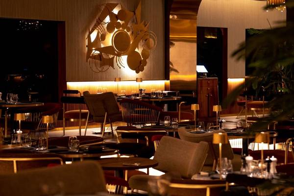 Innenansicht des Restaurants des St. Regis Doha mit goldenen Leuchten und modernen Möbeln.