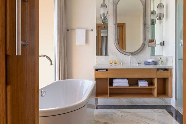 Badezimmer im St. Regis Doha Hotel mit Badewanne, Waschbecken und Spiegeln.