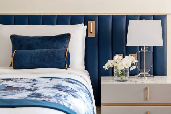 Bett im St. Regis Doha Hotel mit blauen Kissen und weißer Bettwäsche.