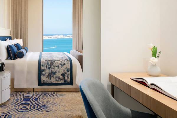 Hotelzimmer mit Meerblick im St. Regis Doha mit einem Bett, Schreibtisch und einem offenen Buch.