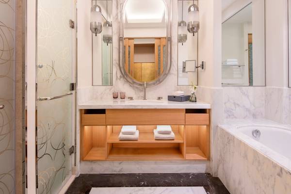 Das Badezimmer im St. Regis Doha mit einer Badewanne, Waschbecken und Spiegeln.