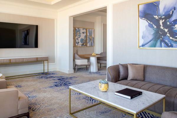 Wohnzimmer im St. Regis Doha mit Fernseher, Sofa, Couchtisch und Kunstwerken.