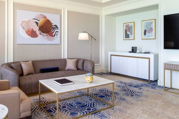 Das Wohnzimmer im St. Regis Doha mit einem braunen Sofa, einem Marmortisch und einer modernen Wandkunst.