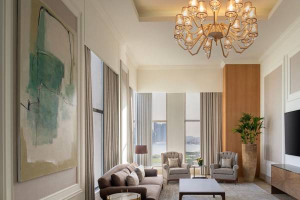 Wohnzimmer im St. Regis Doha mit großem Sofa, zwei Sesseln, Couchtisch, Fernseher und Pflanzen