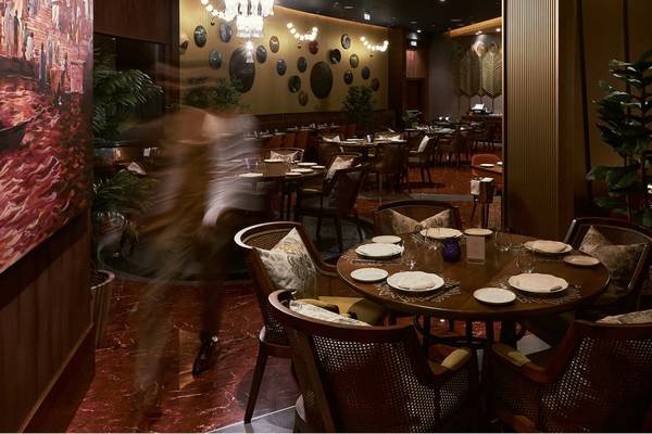 Innenansicht des Restaurants im St. Regis Doha mit runden Tischen und Stühlen, gerahmt von kunstvollen Wanddekorationen.