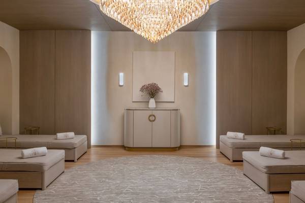 Wellnessbereich im St. Regis Doha mit runden Betten, einem großen Kronleuchter und einer Vase mit Blumen.