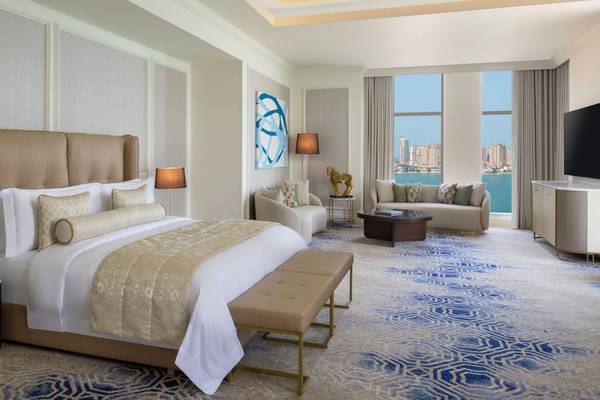 Schlafzimmer im St. Regis Doha mit großem Bett, Fenstern und Blick auf die Stadt.