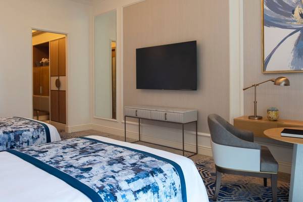 Zweibettzimmer im St. Regis Doha mit Fernseher, Schreibtisch und Nachttisch.