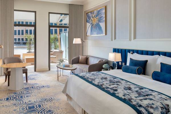 Innenansicht der Suite im St. Regis Doha Hotel mit großem Bett, Wohnzimmerbereich und Blick auf die Stadt.
