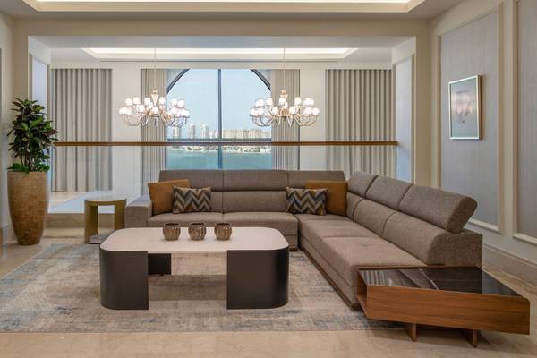 Wohnzimmer des St. Regis Doha mit Meerblick, großer Couch, Tisch und Pflanzen.