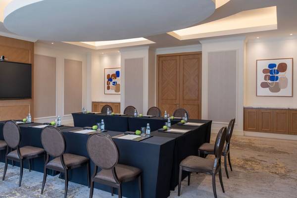 Konferenzraum im St. Regis Doha mit runden Tisch, Stühlen und einer großen Leinwand.