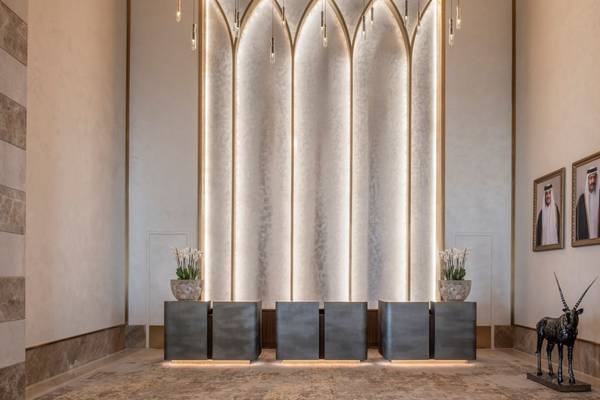 Empfangsbereich des St. Regis Doha Hotels mit Marmorwänden, illuminierten Säulen und Kunstwerken.