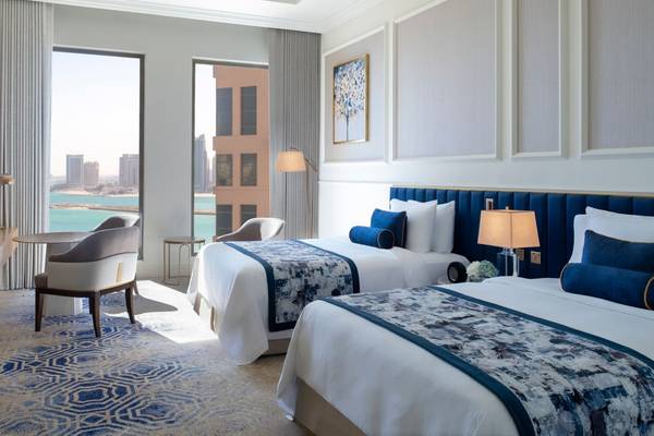 Zwei Betten in einem Hotelzimmer mit Blick auf die Stadt und das Meer.