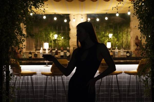 Frau im St. Regis Doha bei der Bar mit einem Glas in der Hand