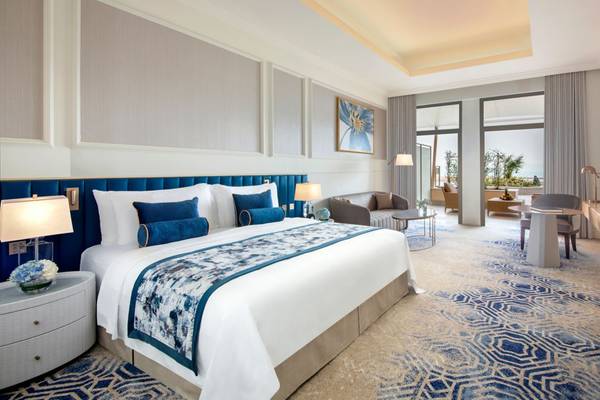 Schlafzimmer im St. Regis Doha mit großem Bett, blauen Kissen und eleganter Einrichtung.