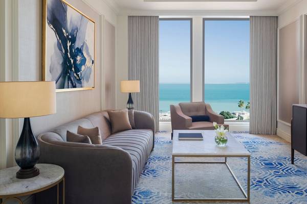 Wohnzimmer mit Meerblick im St. Regis Doha, mit Sofa, Sessel, Tisch, Lampen und Fernseher.