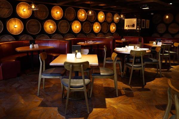 Innenraum des St. Regis Doha Hotel Restaurants mit gepolsterten roten Bänken und Holztischen.