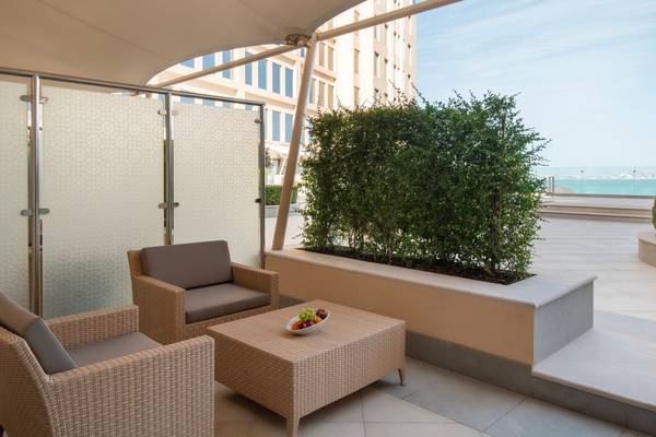 Terrasse des St. Regis Doha Hotels mit Möbeln und Blick auf das Meer.