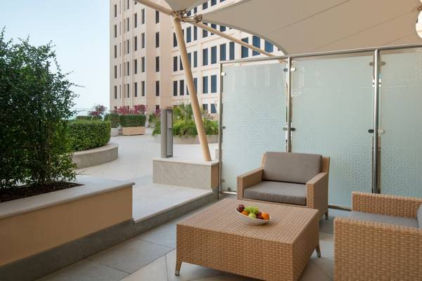 Terrasse des St. Regis Doha mit zwei Korbsesseln und einem Tisch mit Obst.