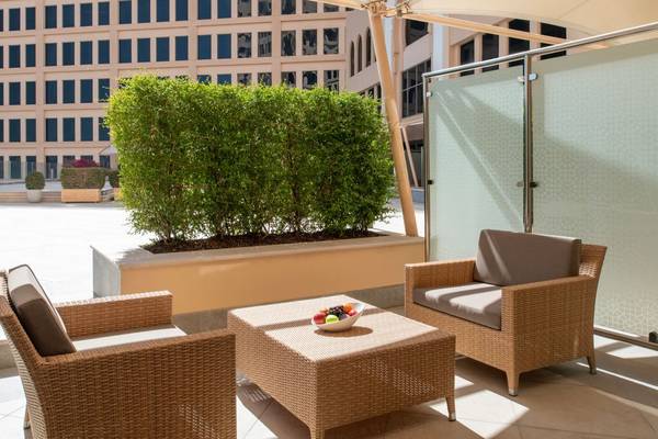 Terrasse des St. Regis Doha mit zwei Korbsofas und einem Tisch mit Obst.