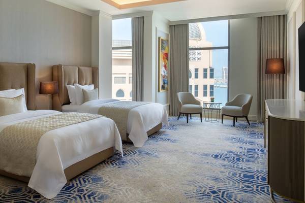 Doppelzimmer im St. Regis Doha mit zwei Betten, Blick auf die Stadt und modernem Interieurdesign.
