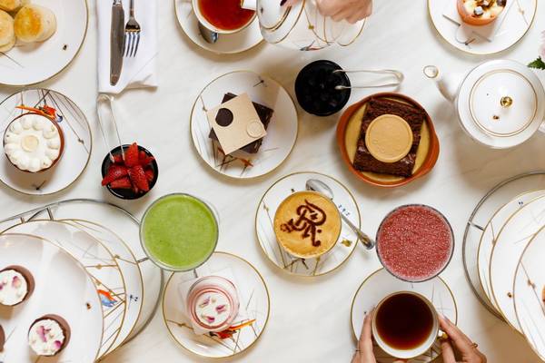 Luftaufnahme des Nachmittagstee-Angebots im St. Regis Doha mit verschiedenen Desserts, Getränken und Geschirr.