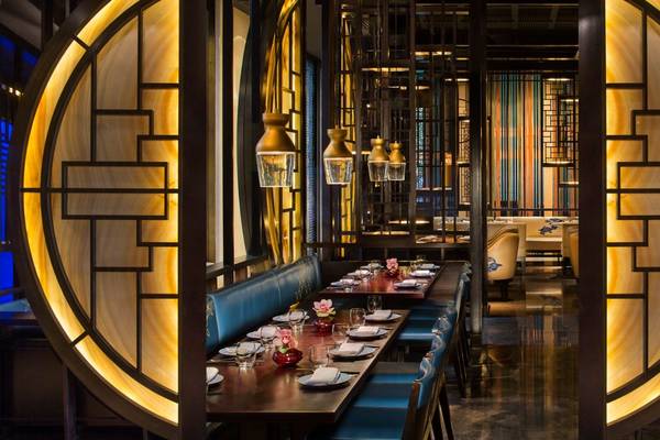 Innenansicht des St. Regis Doha Restaurants mit runden gelben Wänden und blauen Sitzbänken