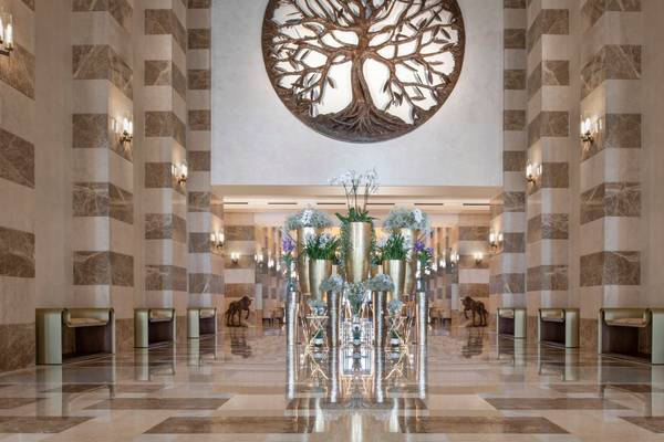 Lobby des St. Regis Doha Hotels mit Marmorboden und zentralem Baumwandbild.