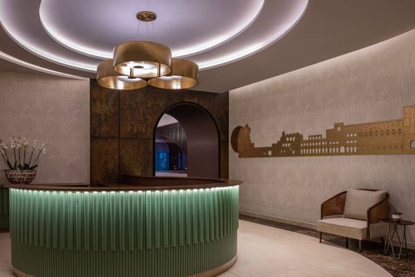 Lobby des St. Regis Doha Hotels mit grünem Empfangstresen und brauner Wanddekoration.