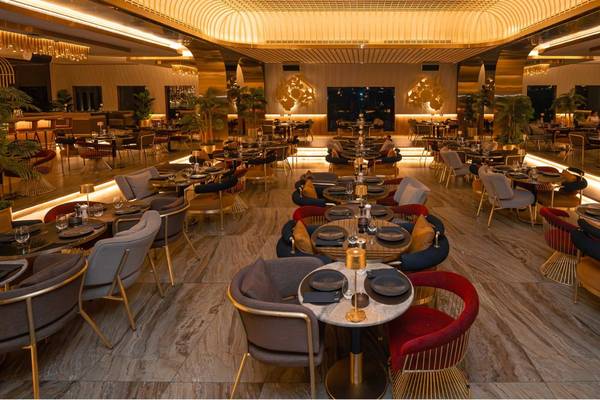 Innenansicht des Restaurants im St. Regis Doha mit goldfarbenen Möbeln und gedeckten Tischen.