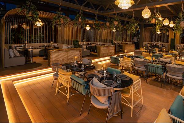 Innenbereich des St. Regis Doha Hotels mit abendlicher Beleuchtung und vielen Tischen und Stühlen.