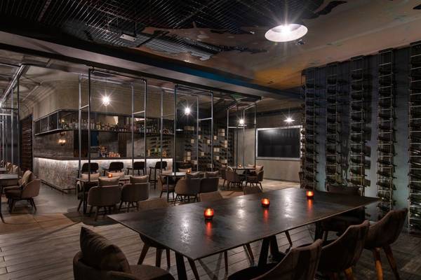 Innenbereich der Bar im St. Regis Doha mit Tisch, Stühlen und Weinflaschen an der Wand