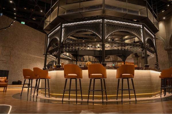 Bar im St. Regis Doha mit geschwungenen Holzstühlen und einer thematischen Struktur.