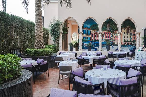 Außenbereich des St. Regis Doha Gartenrestaurants mit Tisch, Stühlen und Wandmalerei