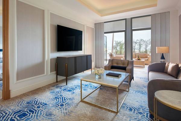 Der Wohnbereich im St. Regis Doha mit Fernseher, Sofa und Tisch.