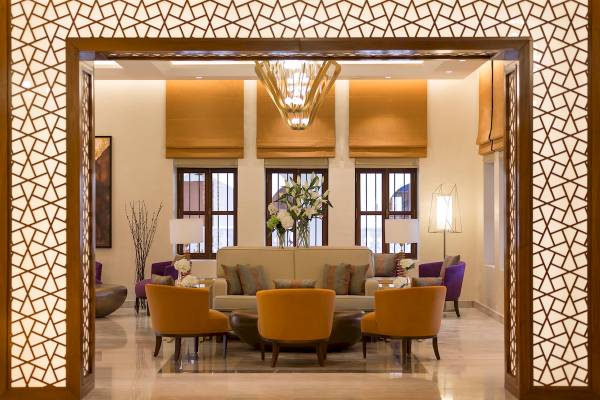 Souq Al Wakra Hotel Qatar By Tivoli Lobby mit Couch, Sesseln und Lampen.