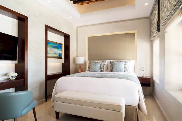 Ein stilvolles Zimmer im Souq Al Wakra Hotel Qatar By Tivoli mit einem großen Bett, Kissen und einem Nachttisch.