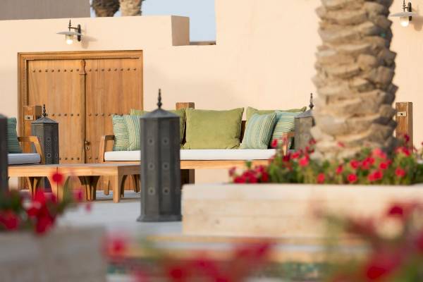 Außensitzbereich des Souq Al Wakra Hotel Qatar By Tivoli mit einem großen Sofa und Kissen.