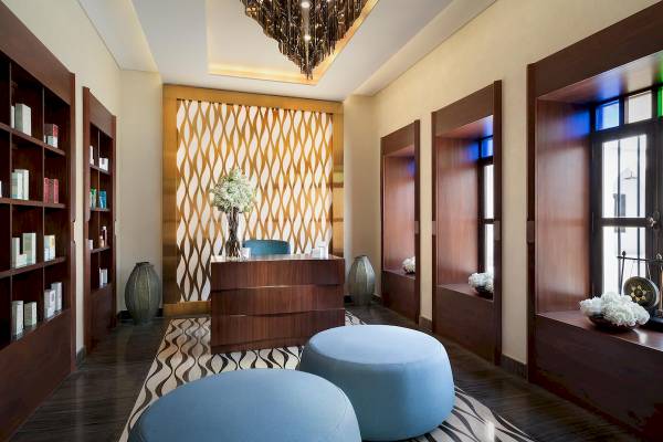 Innenansicht der Lobby des Souq Al Wakra Hotel Qatar By Tivoli mit Rezeptionstresen, blauen Sitzkissen und Bücherregalen