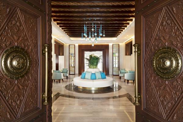 Lobbyansicht des Souq Al Wakra Hotel Qatar By Tivoli mit dekorierten Türen und zentralem Möbelstück.