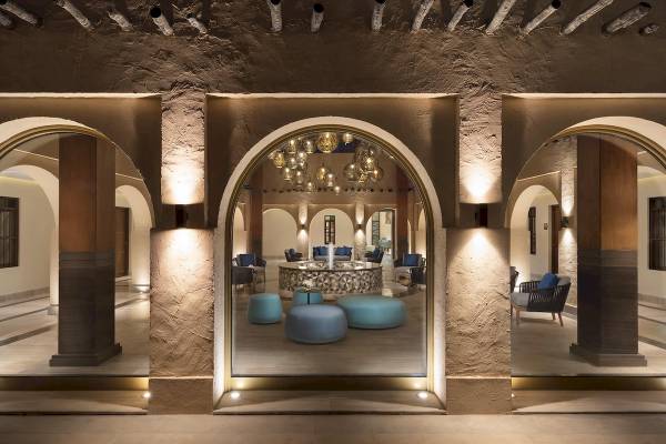 Lobby des Souq Al Wakra Hotel Qatar By Tivoli mit gebogenen Eingängen und blauen Sitzmöbeln.