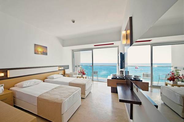 Zwei Betten in einem Hotelzimmer von Yalihan Una mit Meerblick und großer Glastür.