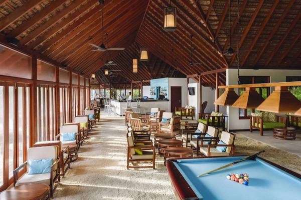 Hotellounge des Summer Island Maldives mit Billardtisch, Holzmöbeln und einer Bar.